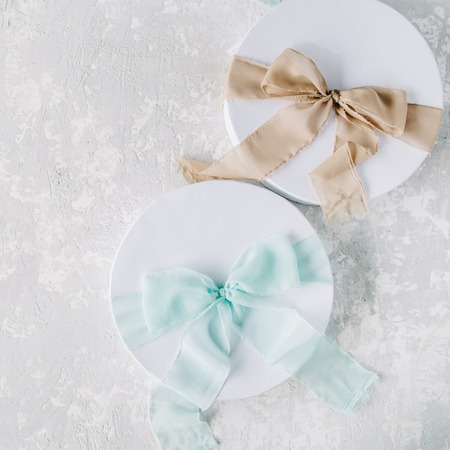 white gift cardboard box with brown and blue bow on concrete background. flat lat, top viewの写真素材