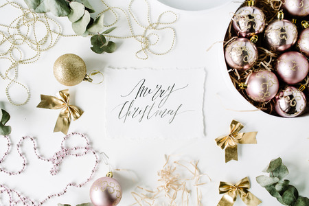 calligraphy words merry christmas and frame made of christmas decoration with christmas balls, tinsel, bow, eucalyptus. christmas wallpaper. flat lay, top viewの写真素材