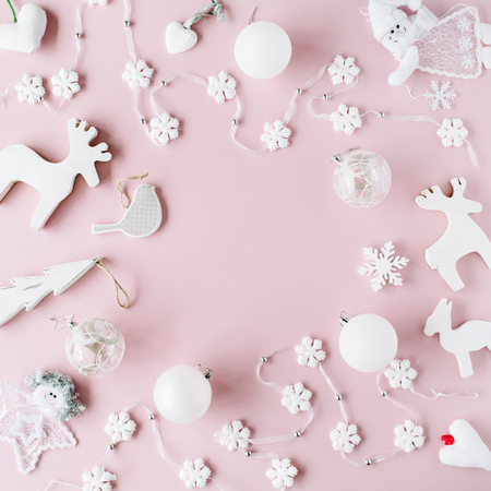 frame made of white christmas decoration with christmas glass balls, tinsel, bow, elk, bird on pink background. christmas wallpaper. flat lay, top viewの写真素材