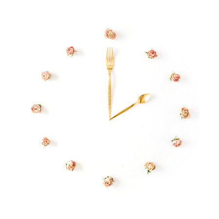 flat lay clock face made of rose buds, spoon and fork. top viewの写真素材