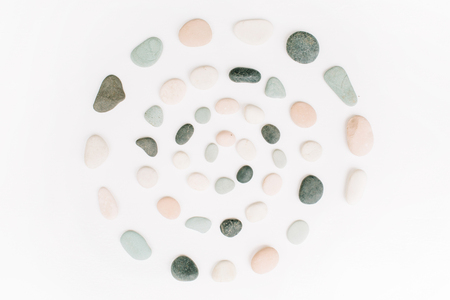 Creative spiral arrangement of colored stones. Mint, pink, beige and grey stones on white. Flat lay, top viewの写真素材