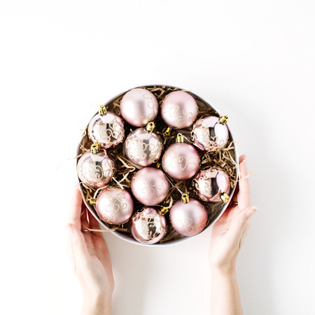 female hands holding round box with bright christmas balls on white background. flat lay, top viewの写真素材