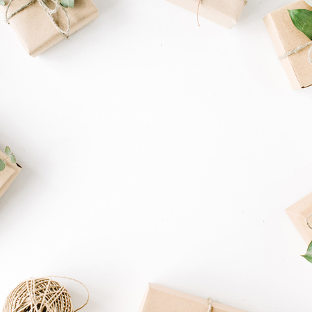 creative arrangement frame of craft boxes and green branches on white background. flat lay, top view