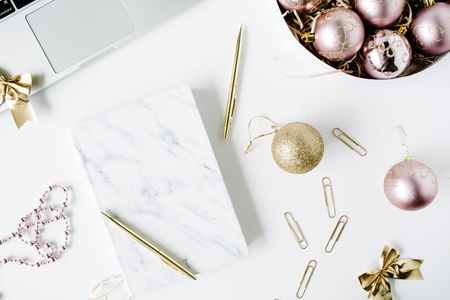 feminine workspace with laptop, marble diary, golden pen, christmas decoration, christmas balls, tinsel, bow on white background. flat lay, top viewの写真素材
