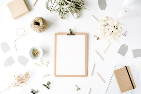 Flat lay, top view office table desk. feminine desk workspace mock up with clipboard, twine, pencils, floral bouquet, craft diary and clips on white background.の写真素材