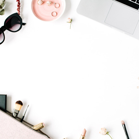 Flat lay, top view office table desk frame. feminine desk workspace with laptop, clutch, cosmetics, phone, sunglasses, lipstick rose buds on white background.の写真素材