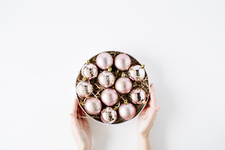 female hands holding round box with bright christmas balls on white background. flat lay, top viewの写真素材