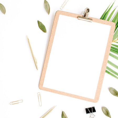 clipboard with empty copy space blank, golden pen and clips, petals and palm branch on white background. flat lay, top viewの写真素材