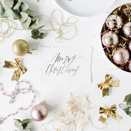 calligraphy words merry christmas and frame made of christmas decoration with christmas balls, tinsel, bow, eucalyptus. christmas wallpaper. flat lay, top viewの写真素材