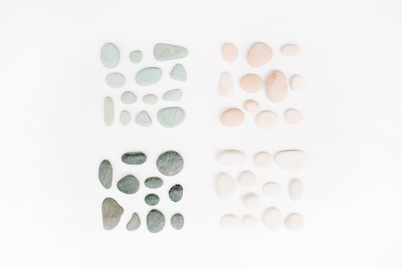 Creative arrangement of colored stones. Mint, pink, beige and grey stones on white. Flat lay, top viewの写真素材