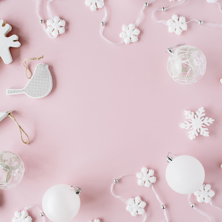 frame made of white christmas decoration with christmas glass balls, tinsel, bow, elk, bird on pink background. christmas wallpaper. flat lay, top viewの写真素材