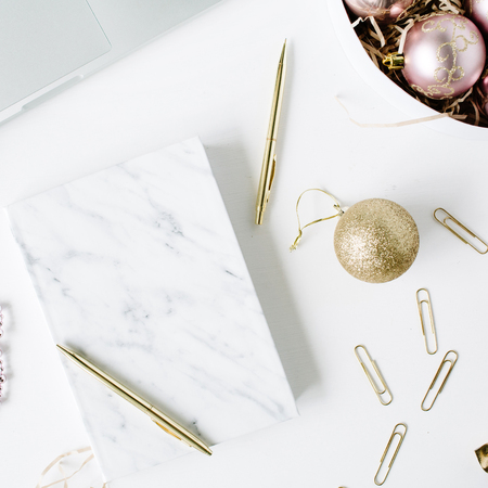 feminine workspace with laptop, marble diary, golden pen, christmas decoration, christmas balls, tinsel, bow on white background. flat lay, top viewの写真素材