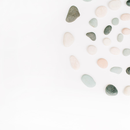 Creative spiral arrangement of colored stones. Mint, pink, beige and grey stones on white. Flat lay, top viewの写真素材