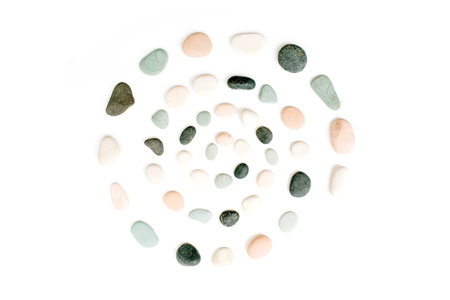 Creative spiral arrangement of colored stones. Mint, pink, beige and grey stones on white. Flat lay, top viewの写真素材