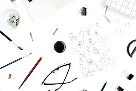 Flat lay, top view office table desk. Workspace with painting, notebook, laptop, scissors, glasses, pen on white background.の写真素材