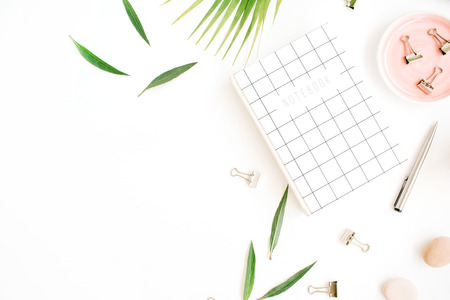 Flat lay, top view office table desk. Workspace with notebook, palm branch and clips on white background.の写真素材