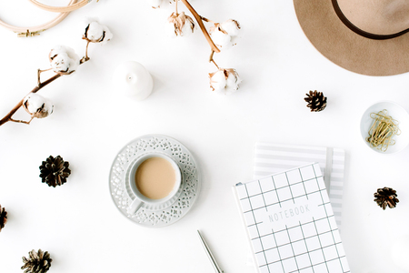 Flat lay trendy creative feminine accessories arrangement with coffee, cotton branch and diary. Hat, cotton branch, notebook, coffee cup, fir cone, golden clips on white background. Top viewの写真素材