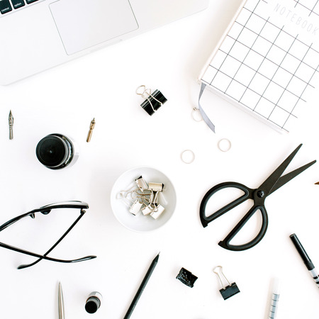 Flat lay, top view office table desk. Workspace with notebook, laptop, scissors, glasses, pen on white background.の写真素材