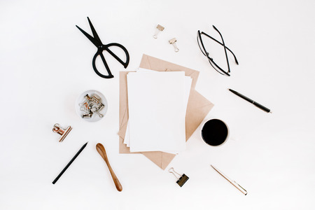 Workspace with clean paper blank, coffee, craft envelope, scissors, office supplies on white background. Flat lay, top view office table desk.の写真素材