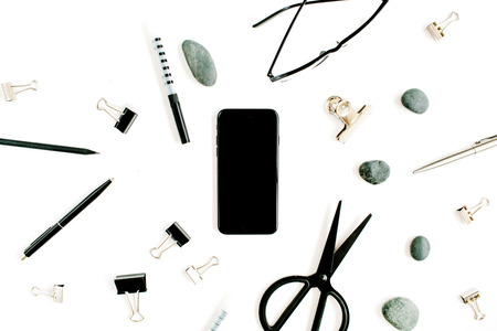 White office desk with supplies. mobile phone, glasses, scissors and office supplies on white background. Flat lay, top view office table desk.の写真素材