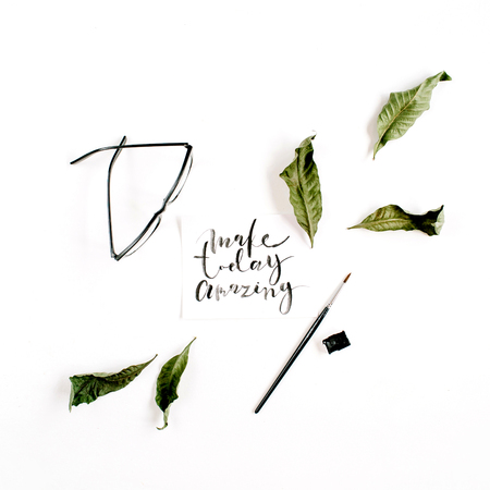 Inspirational quote "Make Today Amazing" written in calligraphic style on paper with green leaf and glasses on white background. Flat lay, top viewの写真素材
