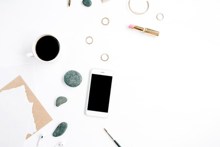 Home office workspace with coffee, mobile phone, craft envelope, stones, headphones and paper blank on white background. Flat lay, top view.の写真素材