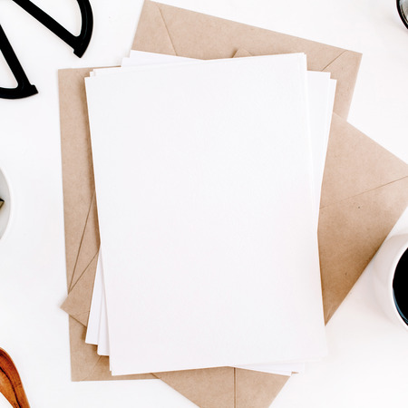 Workspace with clean paper blank, coffee, craft envelope, scissors, office supplies on white background. Flat lay, top view office table desk.の写真素材