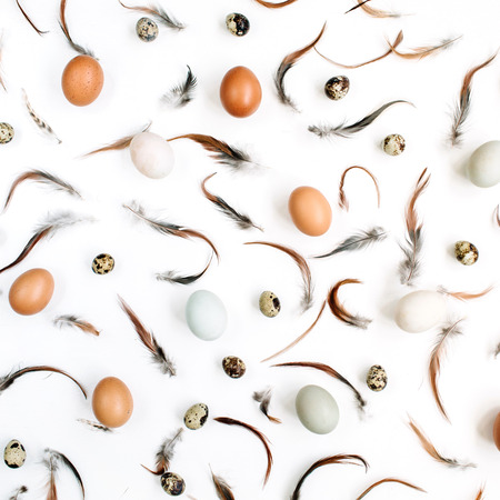 White and brown Easter eggs, quail eggs and feathers on white background. Flat lay, top view. Traditional spring concept.の写真素材