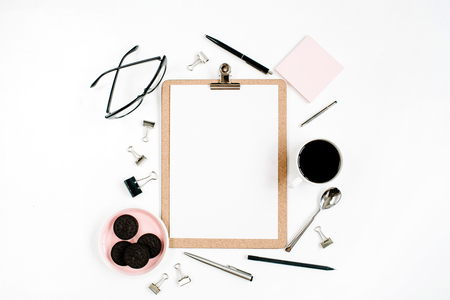 Pale pink home office workspace desk frame with clipboard, coffee, cookies, glasses and office stuff on white background. Flat lay, top view. Entrepreneur office concept.の写真素材