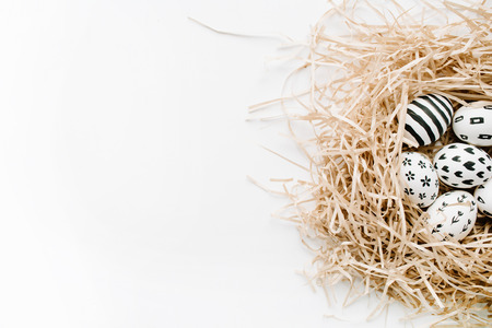 Fancy Easter eggs in nest on white background. Flat lay, top view. Traditional spring concept.