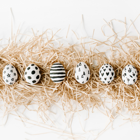 Fancy Easter eggs in nest on white background. Flat lay, top view. Traditional spring concept.