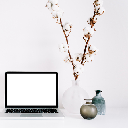 Blogger or freelancer workspace with front view of laptop with blank screen at white background. Minimalistic decorated home office desk.の写真素材