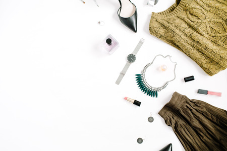 Beauty blog concept. Female clothes and accessories: green skirt and sweater, watches, necklace, lipstick, shoes, sunglasses on white background. Flat lay, top view trendy fashion feminine background.の写真素材