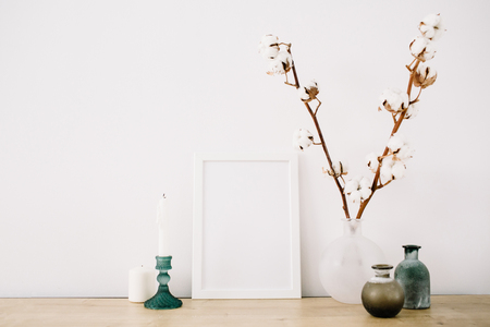 Front view blank mock up of photo frame with cotton and trendy stuff at white background. Minimalistic decorated home office concept.の写真素材