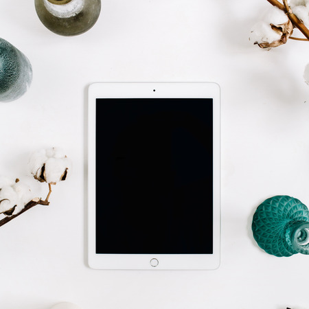 Blogger or freelancer workspace with blank screen tablet and cotton at white background. Flat lay, top view minimalistic decorated home office desk.の写真素材