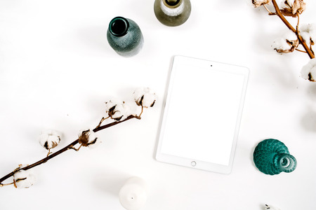 Blogger or freelancer workspace with blank screen tablet and cotton at white background. Flat lay, top view minimalistic decorated home office desk.の写真素材