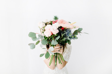 Pretty woman with beautiful flowers bouquet at white wall. Lifestyle composition.の写真素材