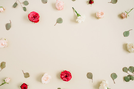 Flowers frame made of beige and red roses, eucalyptus leaf on pale pastel beige background. Flat lay, top view. Floral wreath frame background.の写真素材