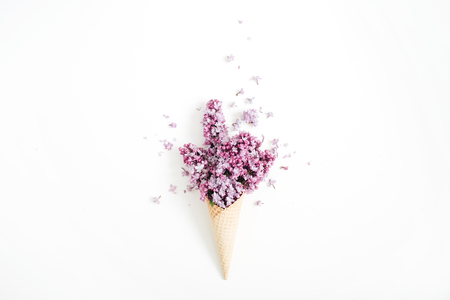 Waffle cone with lilac flower bouquet on white background. Flat lay, top view floral background.の写真素材