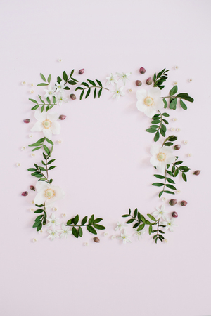 Frame of flowers, branches, leaves and petals with space for text on pink background. Flat lay, top viewの写真素材