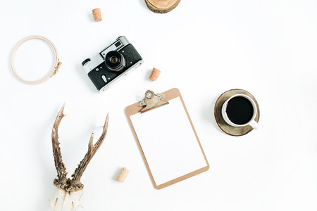 Top view, flat lay hipster photographer concept. Retro camera, goat horns, clipboard and morning coffee cup on white background.の写真素材