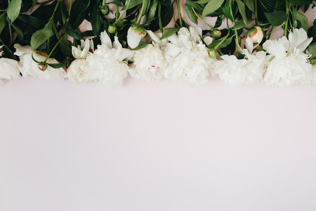 Floral pattern made of white peonies, green leaves, branches on white background. Flat lay, top view. Floral background. Pattern of flowers.の写真素材