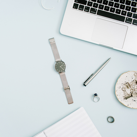 Top view, flat lay home office desk. Women workspace with laptop, white peony flowers bouquet, accessories on blue background.の写真素材