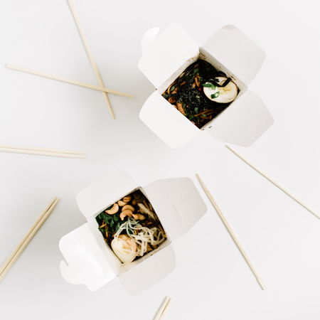 Noodles in box and chopsticks on white background. Flat lay, top view. Chinese takeaway food...