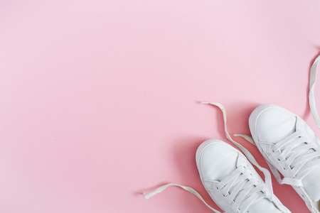 White women's sneakers on pink background. Flat lay, top view minimal background.の写真素材