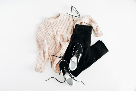 Fashion winter women clothes look on white background. Flat lay, top view. Sweater, sneakers, jeans and glasses.の写真素材