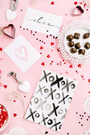 Valentine's Day or Love composition. Chocolate candies, heat symbols, cards on pale pink background. Flat lay, top view.の写真素材