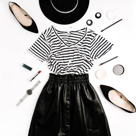 Woman fashion flatlay. Black modern clothes and accessories. Skirt, t-shirt, hat, shoes, lipstick, watches, powder on white background. Flat lay, top view.の写真素材