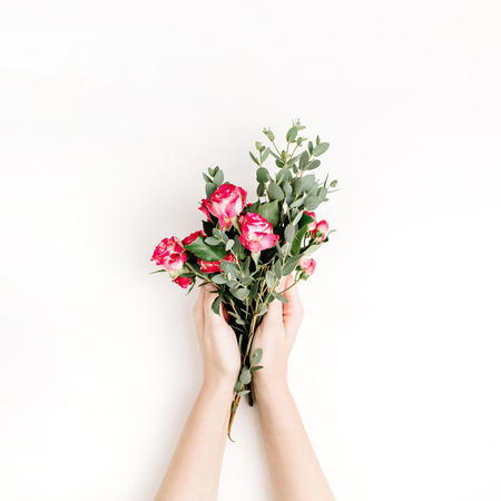 Woman hands hold rose flowers and eucalyptus branch bouquet on white background. Flat lay, top view spring hero header background.の写真素材
