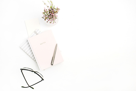 Woman modern minimal home office desk with notebook, glasses, pen and wildflowers bouquet on white background. Flat lay, top view blog composition.の写真素材